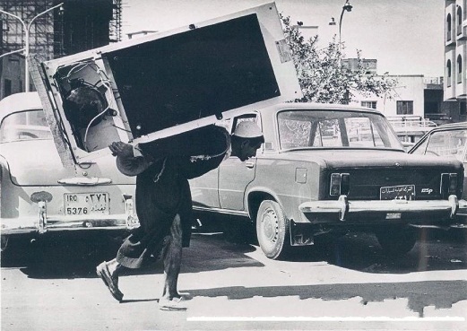 عراقي يحمل ثلاجة على ظهره كآلية نقل في ستينات القرن الماضي في بغداد