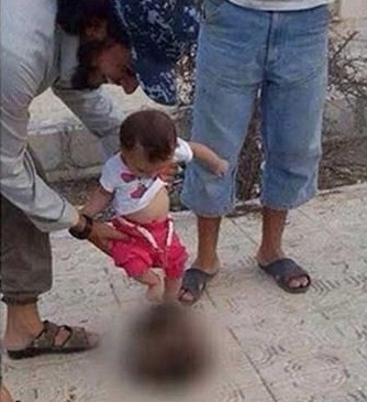 صورة/داعشي يشجع طفله الرضيع على ركل رأس مقطوعة بالرقة
