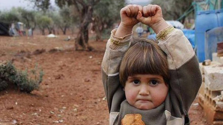 صورة فوتوغرافية لطفلة سورية "استسلمت" أمام عدسة صحفي ظانة انه "سلاح" تهز العالم