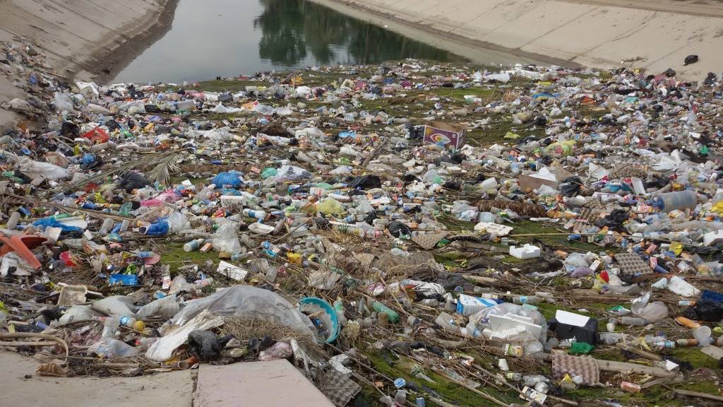 بالصور: تراكم النفايات والمخلفات ببوابة نهر في ناحية الخيرات في كربلاء