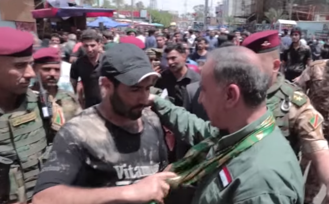 زائر عراقي شاب يضع راية أهل البيت (ع) على كتف وزير الدفاع خالد العبيدي خلال زيارته الإمام موسى الكاظم (ع)