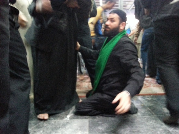 بالصور: شاب شديد العوق  يفتش الزائرين في احد بوابات الحرم الحسيني بكربلاء