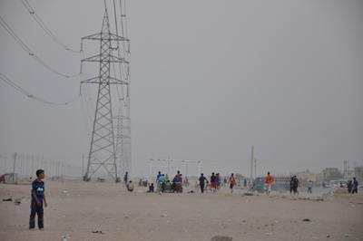 شباب يمارسون لعبة كرة القدم تحت اعمدة الضغط العالي في كربلاء (مصور)