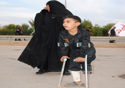 بالصورة :طفل معاق يسير أكثر من( 100 كم)  ليشارك في المسيرة المليونية نحو كربلاء المقدسة