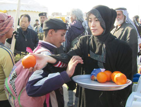 امراة صينية تقوم مع زوجها بخدمة زوار أربعينية الإمام الحسين المتجهين إلى كربلاء