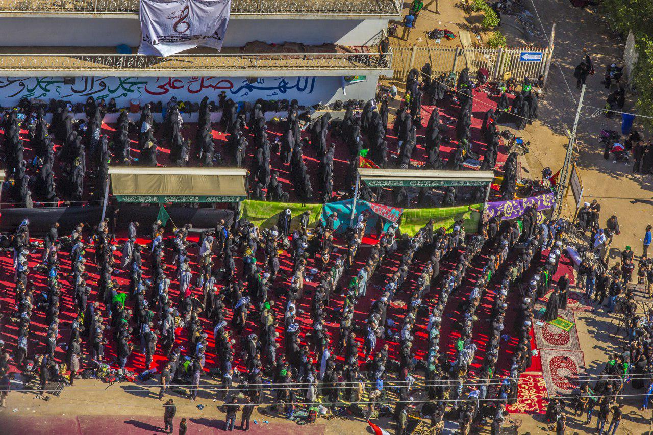 من الجو .. صلاة جماعة موحدة لزوار الاربعين في طريق نجف - كربلاء (فيديو)