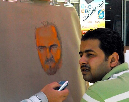 كربلاء :تحت مضلة شمسية رسام يفترش الرصيف ويوجه دعوة تنافسية لممارسة رسم البوتريت في الشارع
