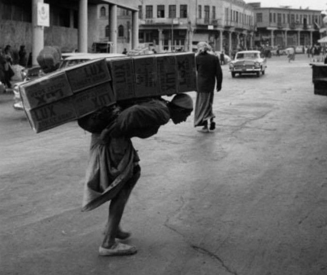 بالصورة :كادح عراقي ينقل بضاعة على ظهره في بغداد عام 1952