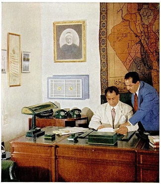 صورة ارشيفية لموظف عرافي بالعهد الملكي واضعا صورة اول رئيس حكومة للعراق خلف مكتبه